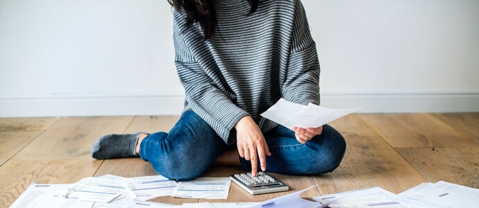 Woman with calculator and bills spread out on the floor