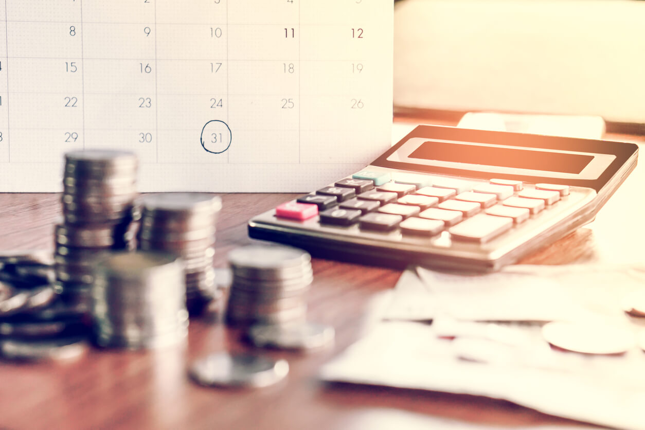 Stacks of quarters, calculator, and calendar with debt