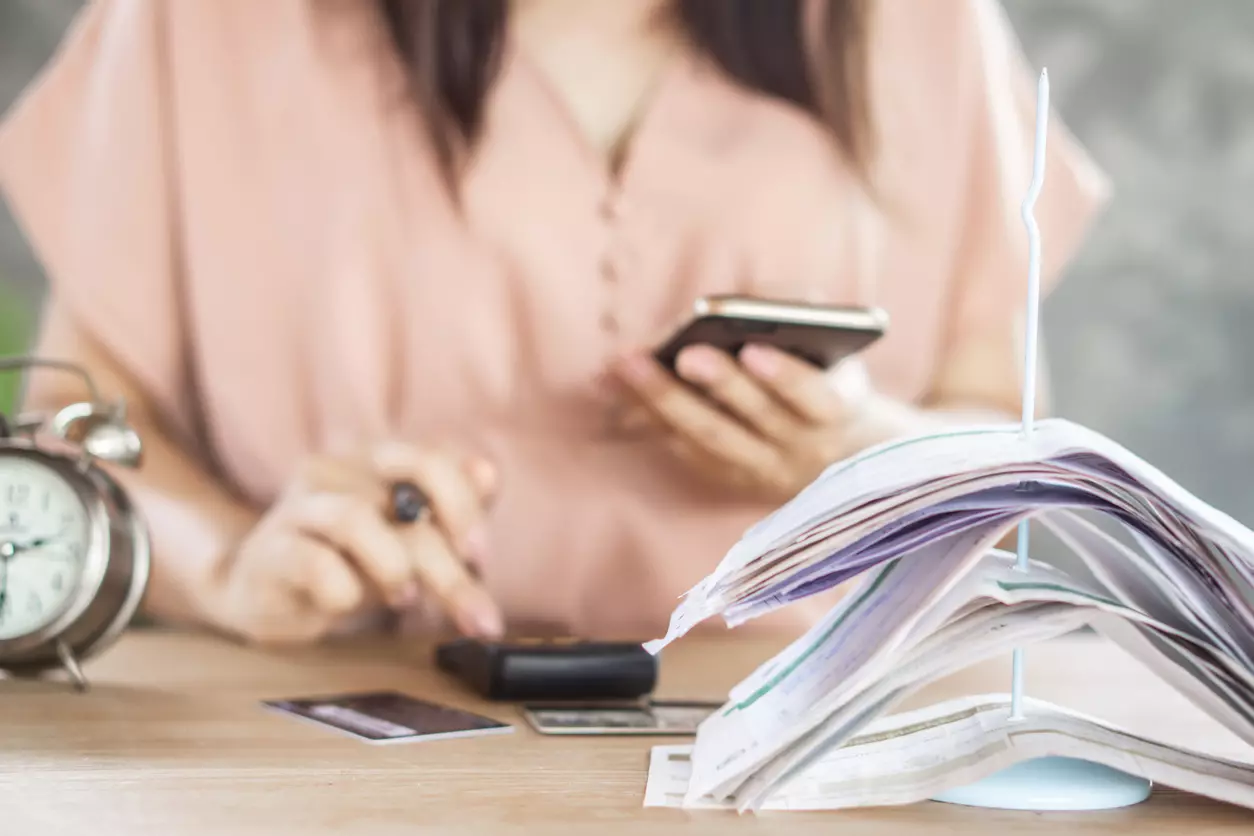 Woman looking over her past due bills, talking to debt collector.